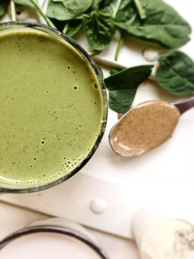 green breakfast smoothie with almond butter on spoon
