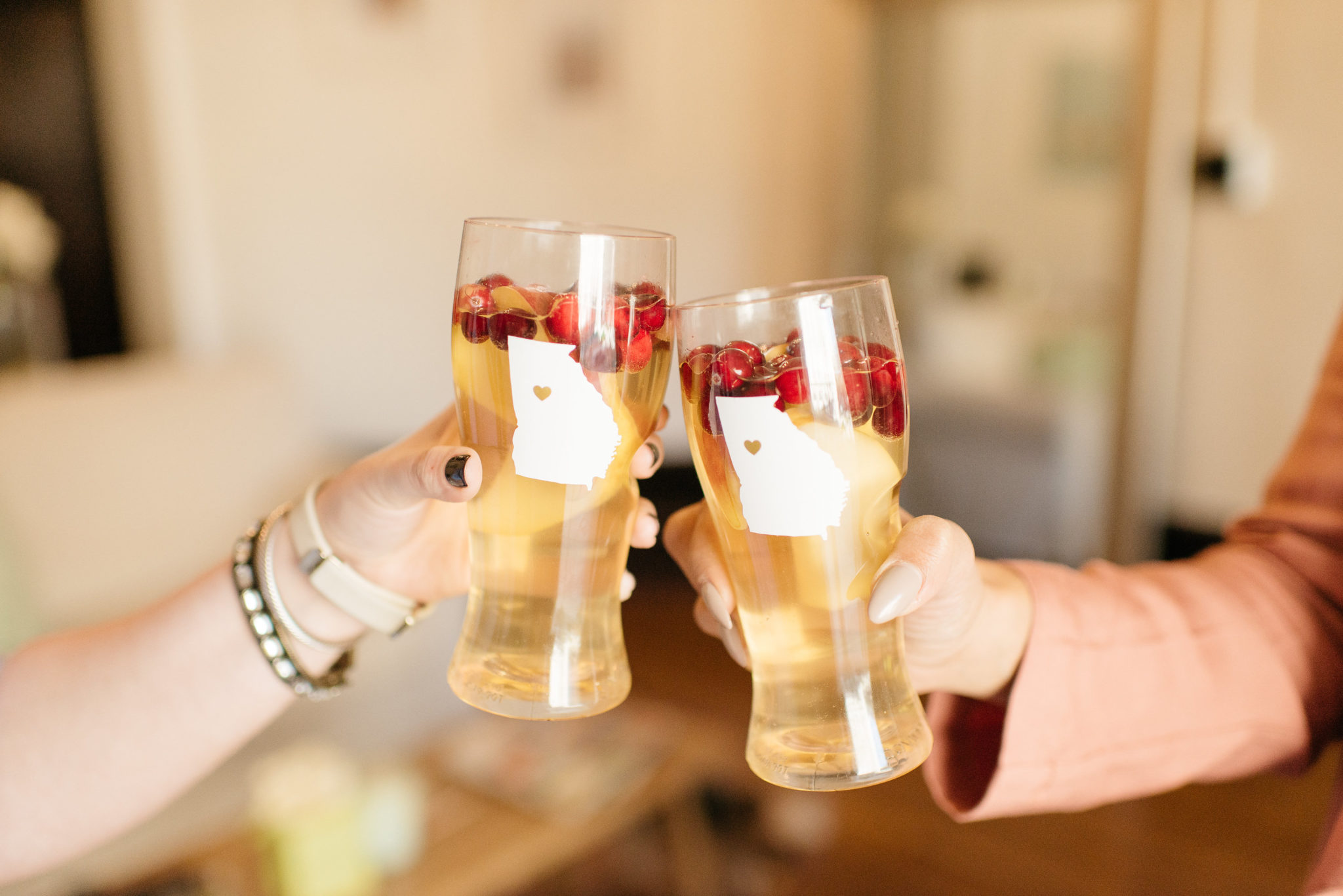two people clinking glasses of apple sangria with cranberries