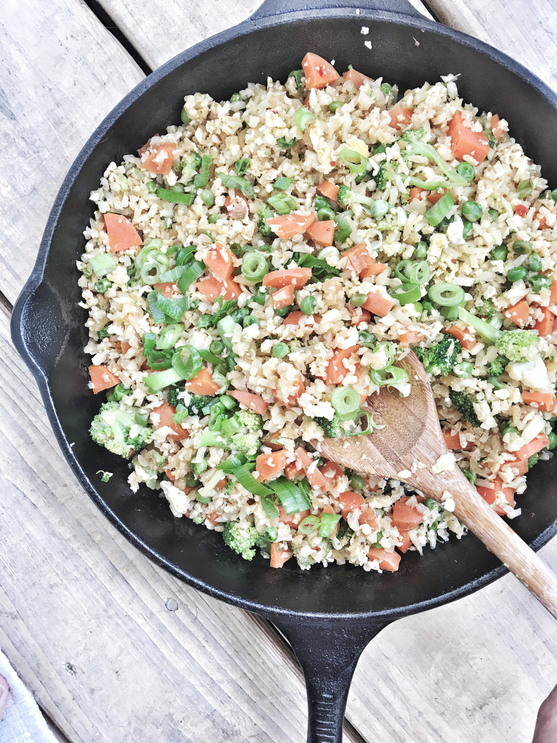 veggie-filled cauliflower fried rice in pan with wooden spoon