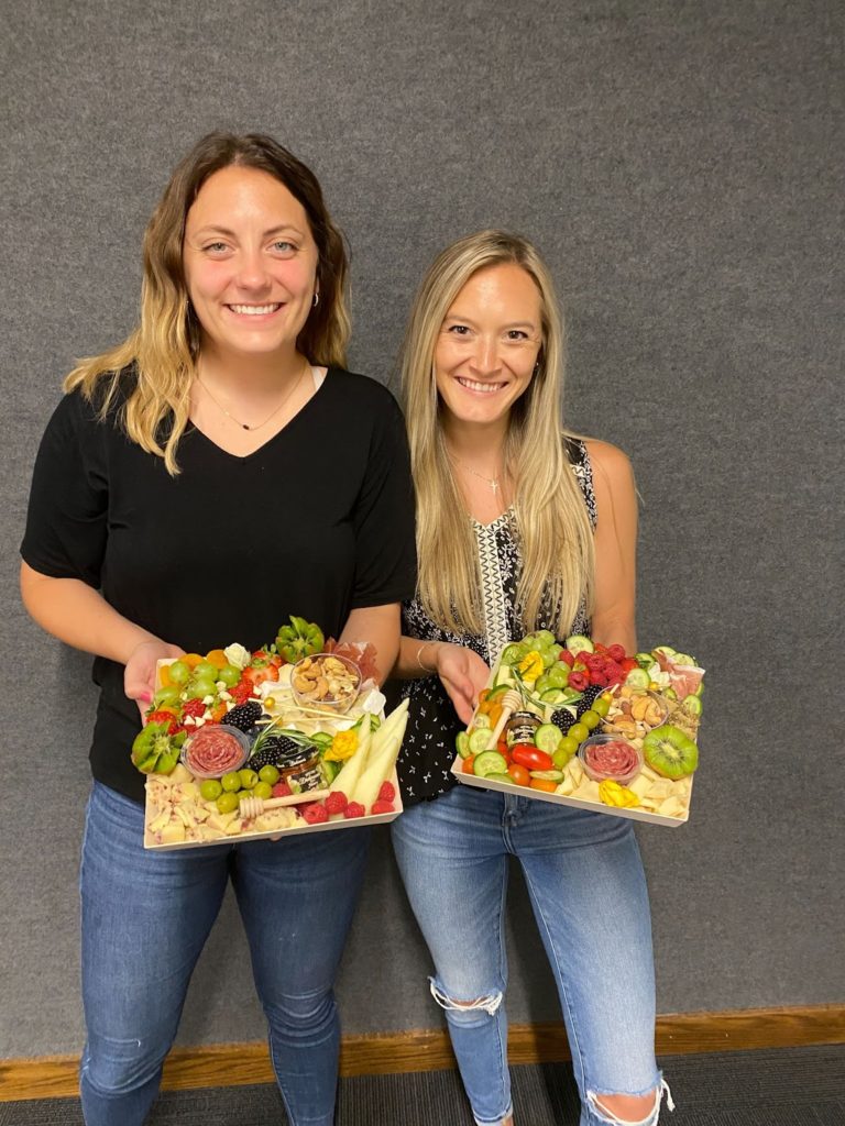 Baylee and a friend holding their finished charcuterie boards in class